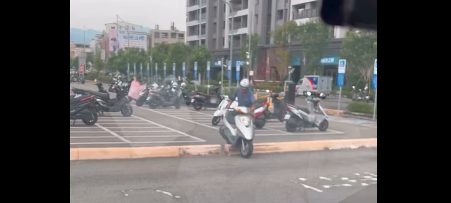 台中太平育賢停車場，一名機車騎士未循正常出口離場，反而直接騎越分隔設施進入道路，過程被民眾拍下。（翻攝Threads／民眾授權提供）