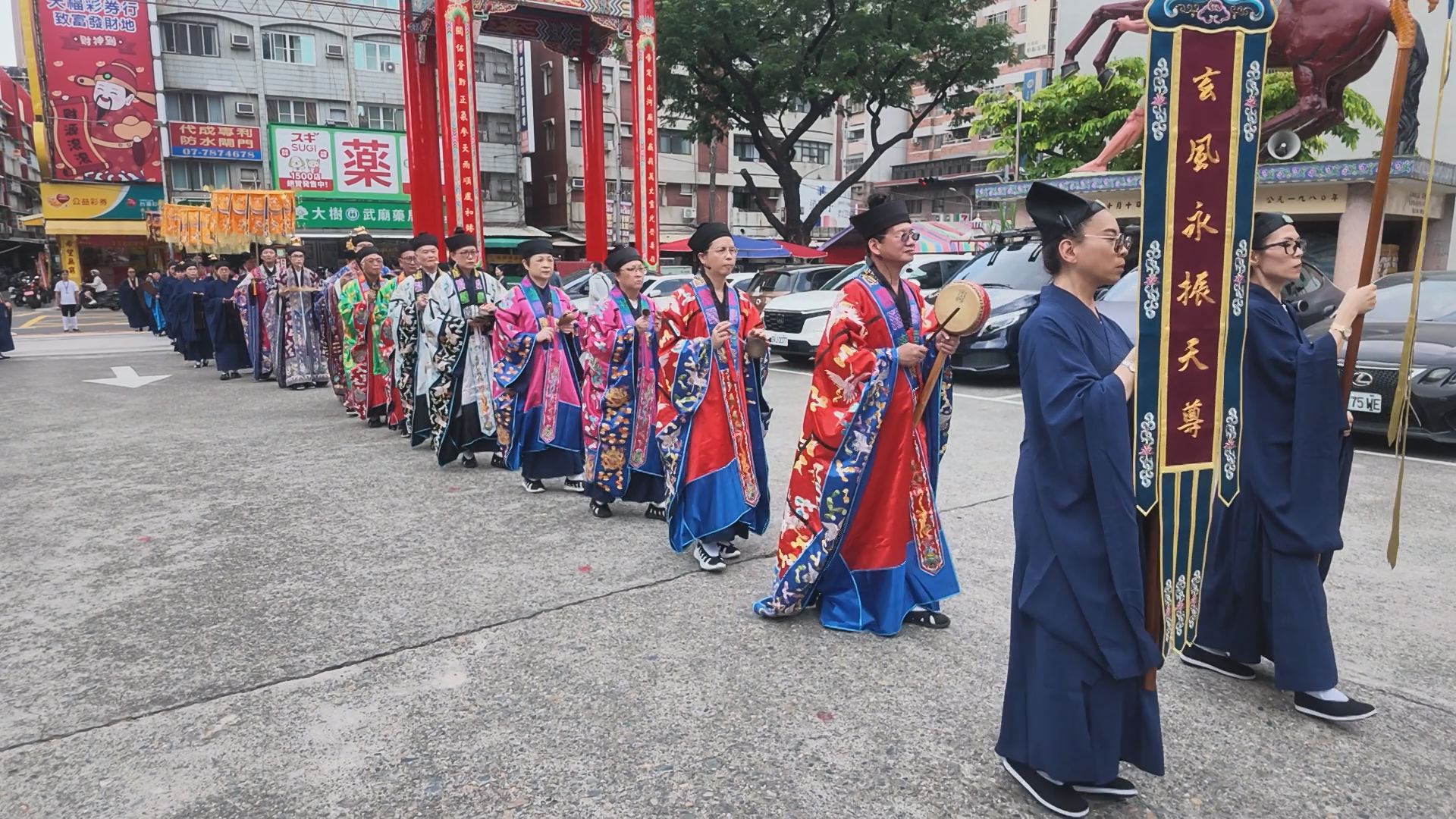 全真派高雄普化院與高雄關帝廟合辦戒典,道長與身穿藏青道衣的戒子們手持幡旗寶蓋,