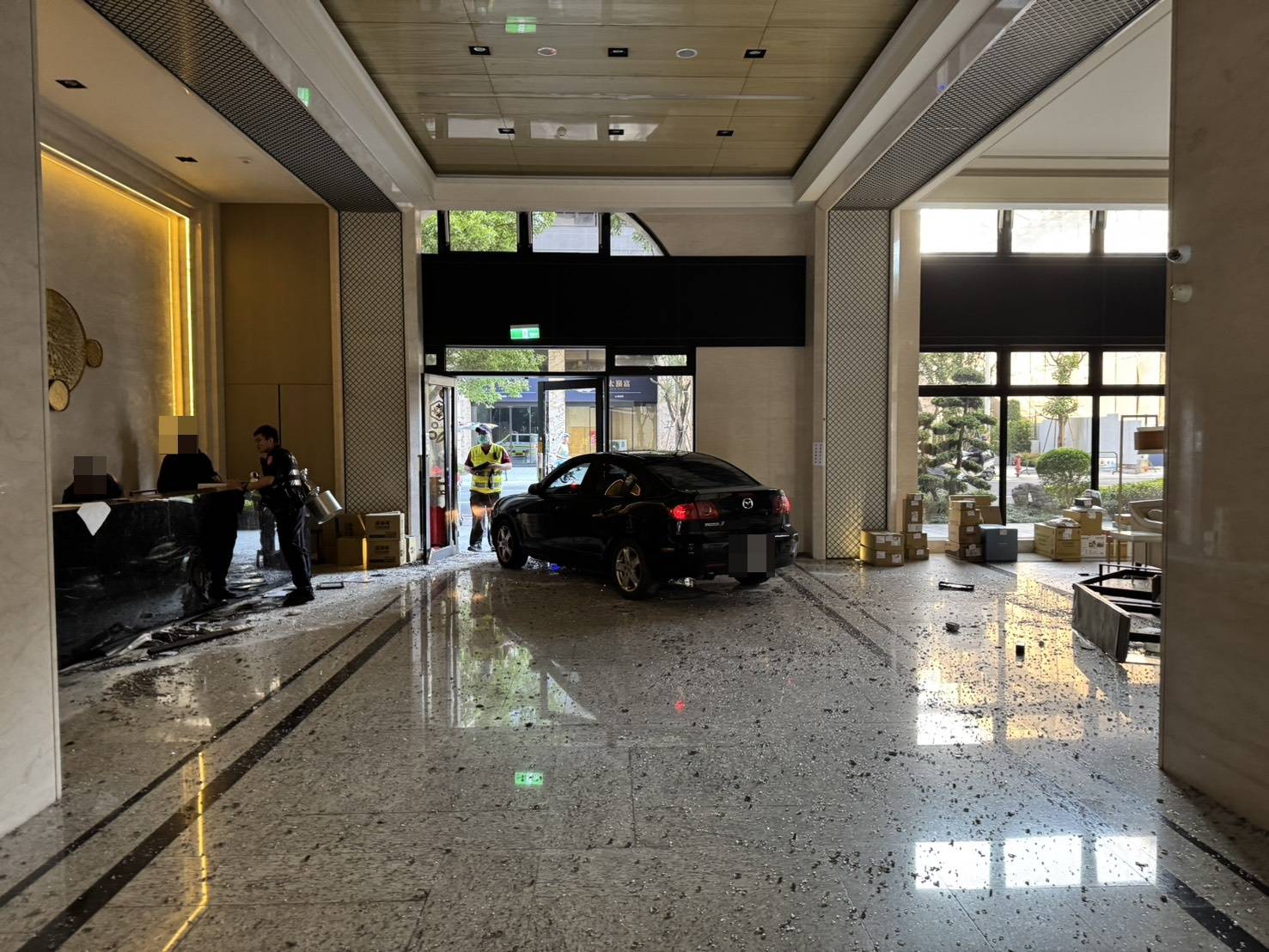 ▲郭男駕車猛撞社區大門衝入社區大廳後，卻無法循原路而去，倒車再撞社區大門仍無法「得逞」，隨即抱著小孩下車逃離現場。（翻攝畫面）