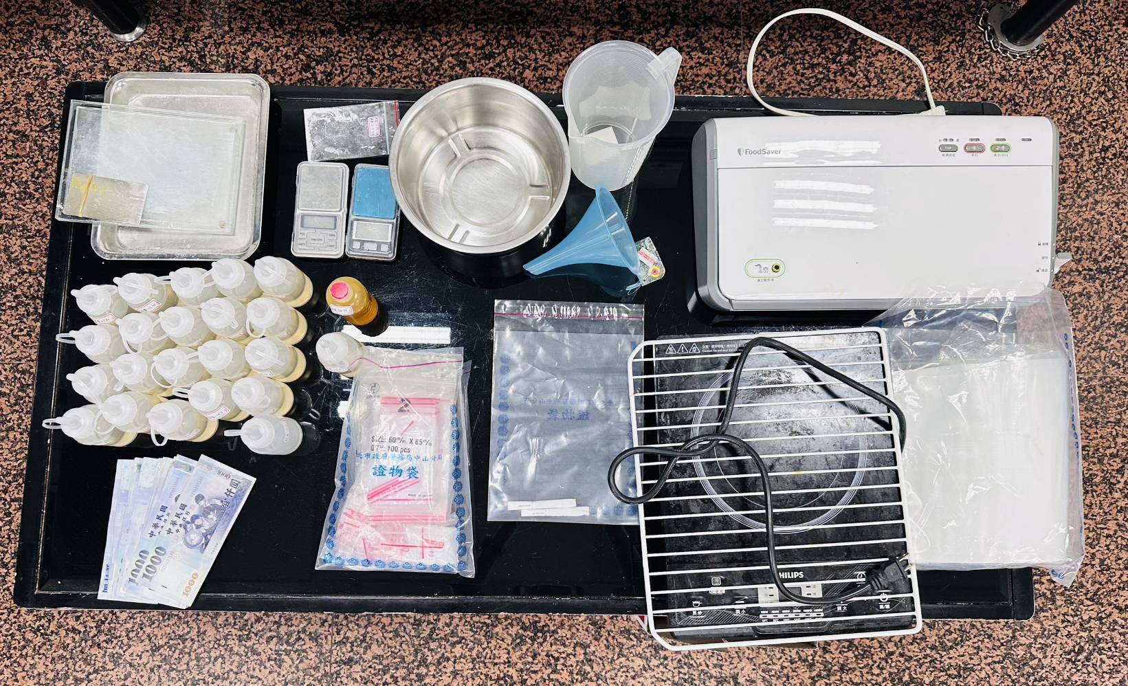 ▲警方在「第4層」藥頭江男藏身處查獲依托咪酯菸油22瓶（總毛重2,405公克）、電子磅秤、封膜機、愷他命研磨盤、分裝袋與現金新台幣4萬1000元。(翻攝畫面)