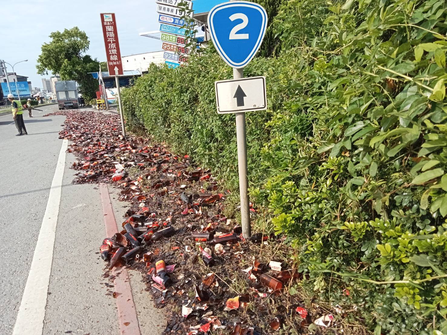 ▲1輛貨櫃車行經青雲路三段時，疑貨櫃門未妥善關閉，過彎時造成車上裝載的數千瓶酒傾瀉而出，黃色塑膠籃與破碎酒瓶散落快車道及人行道，馬路瞬間成為「汪洋酒海」。(翻攝畫面)