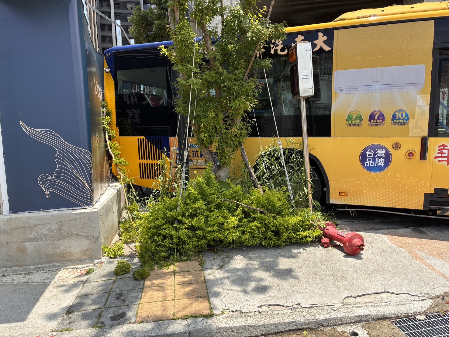 ▲新北市土城區青仁路，昨（22）日11時許發生1起荒謬車禍。一輛大客車無人駕駛竟在道路上緩緩倒退，連續擦撞消防栓與社區警示燈後，最終騎上人行道停下。（翻攝畫面）