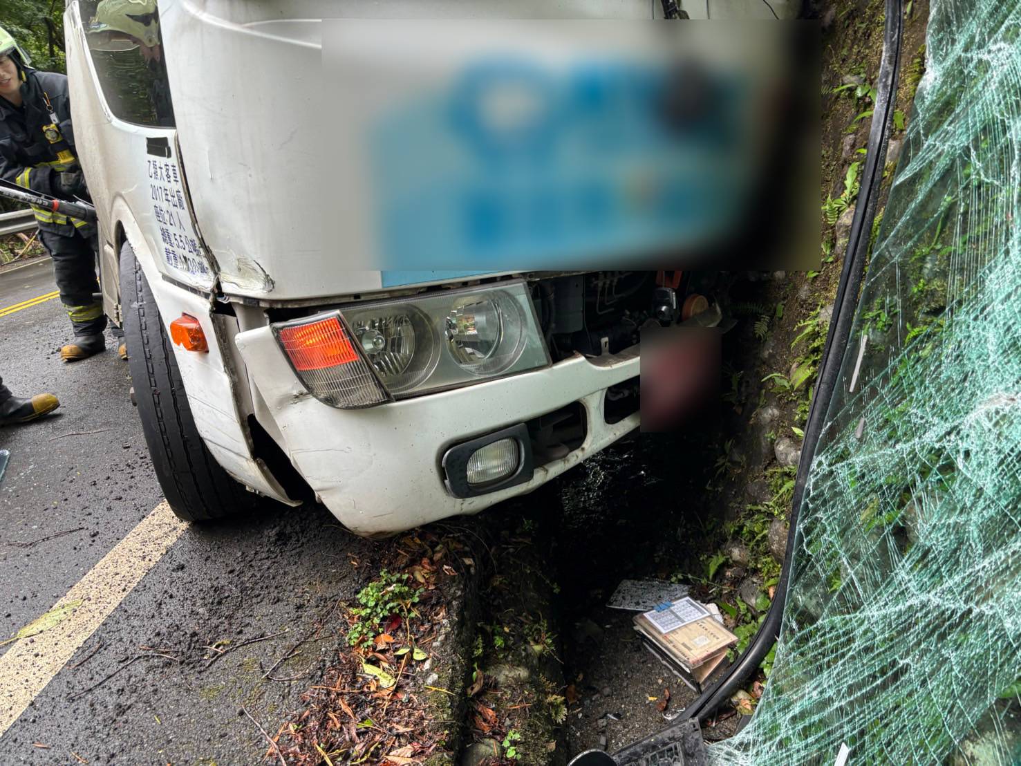 ▲小巴正行經汐平路彎道路段，疑似操作不慎，車輛突然失控撞擊邊坡，車頭爛毀變形導致駕駛雙腿卡住動彈不得。（翻攝畫面）