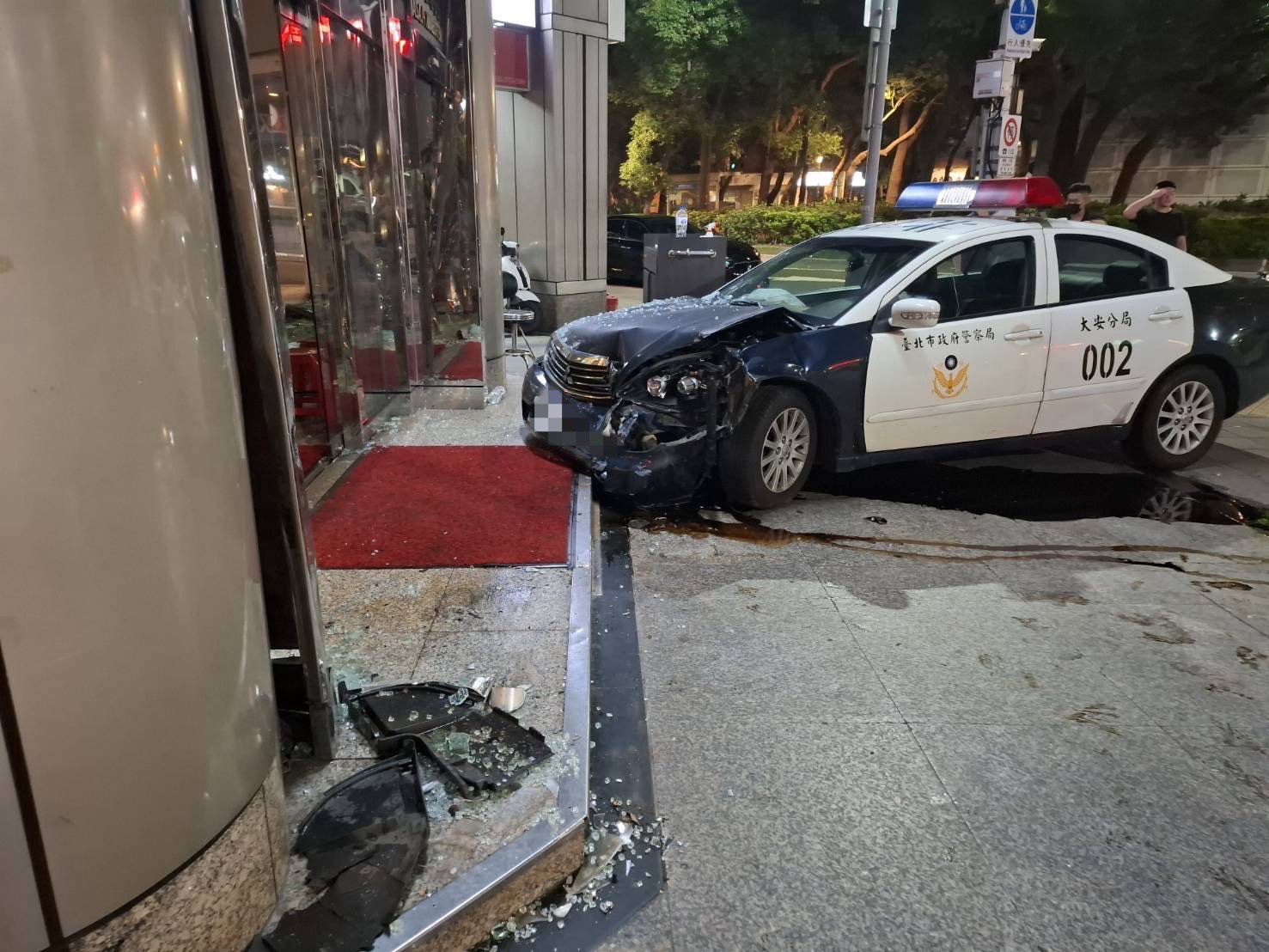 ▲警車車頭嚴重毀損，大樓的門柱及玻璃門也因此破裂。（翻攝畫面）