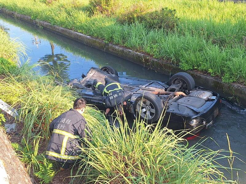 49歲林姓女子駕駛BMW 530i 行經該路段時，不明原因失控自撞路旁護欄，隨後整輛車翻覆，四輪朝天地摔進路旁的灌溉溝渠內。(翻攝畫面)