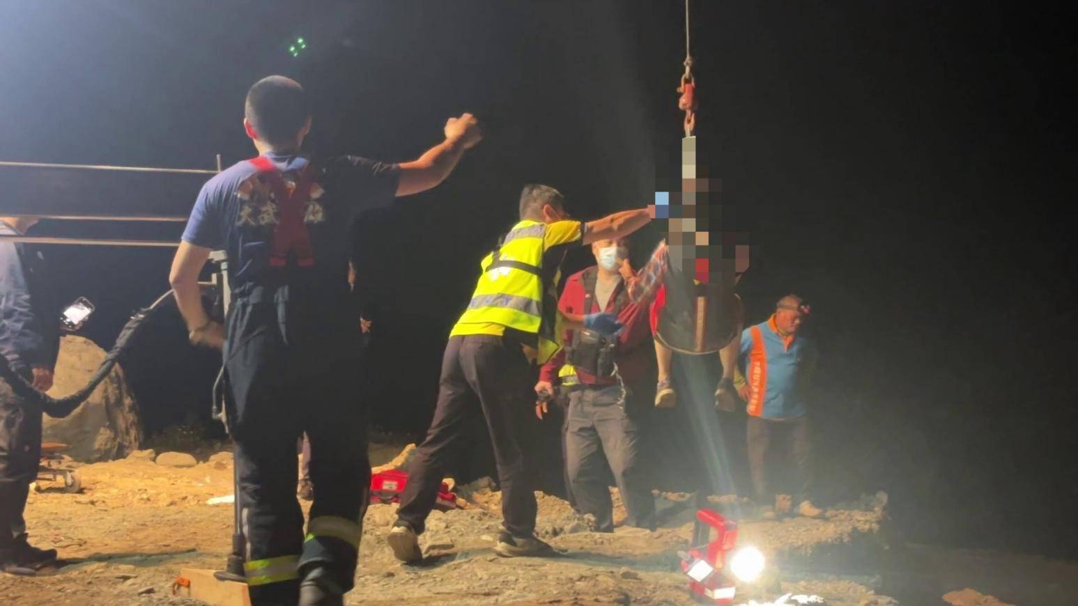 救援人員立即調派器材車，利用機械吊臂將受困於溪床的丈夫及妻子吊掛上岸。