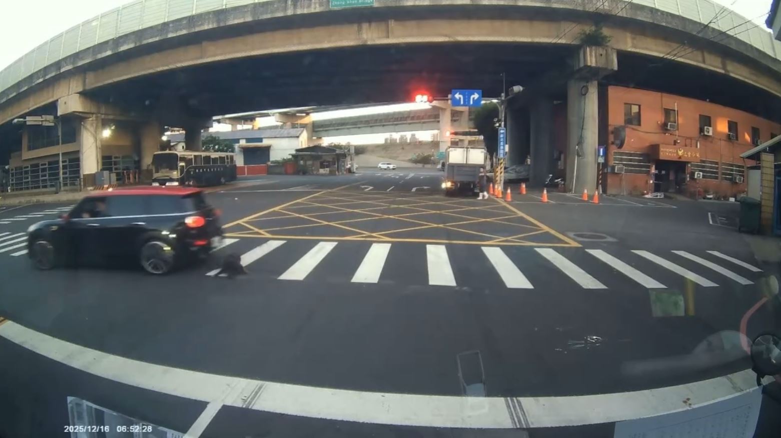 惡質駕駛違規於路口紅燈迴轉，儘管後方車輛不斷鳴按喇叭示警，駕駛仍踩油門加速前行，導致小黑狗先遭前輪捲入車底翻滾，隨即再被後輪二度輾過。