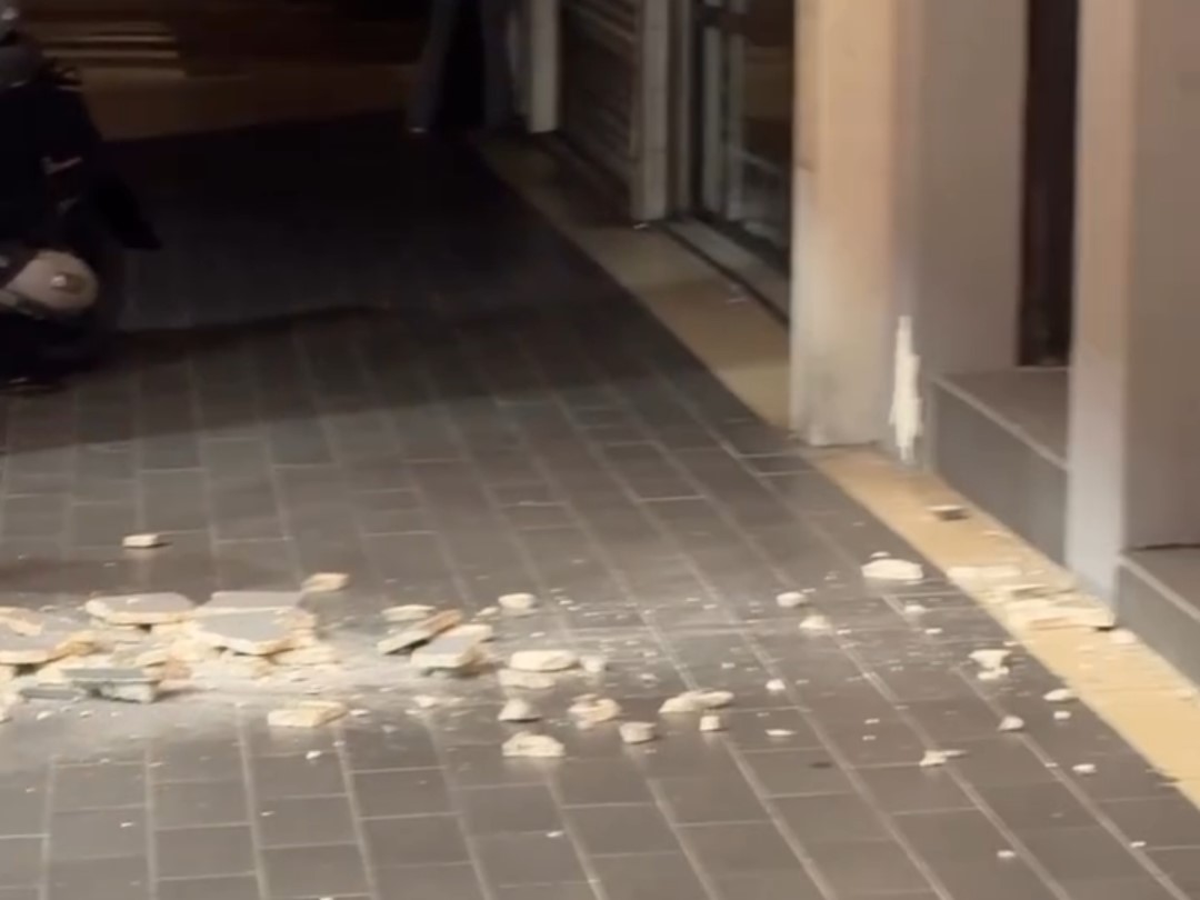 強震造成店門口柱子的外牆磁磚大量剝落，碎塊散落在人行道與騎樓地板上。