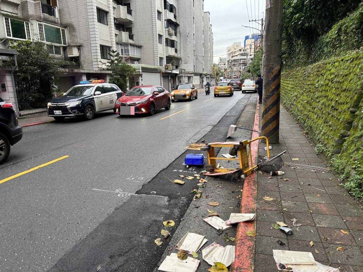 右前車頭直接撞飛路邊的清潔手推車，導致推車零件散落一地、鐵籃扭曲變形。