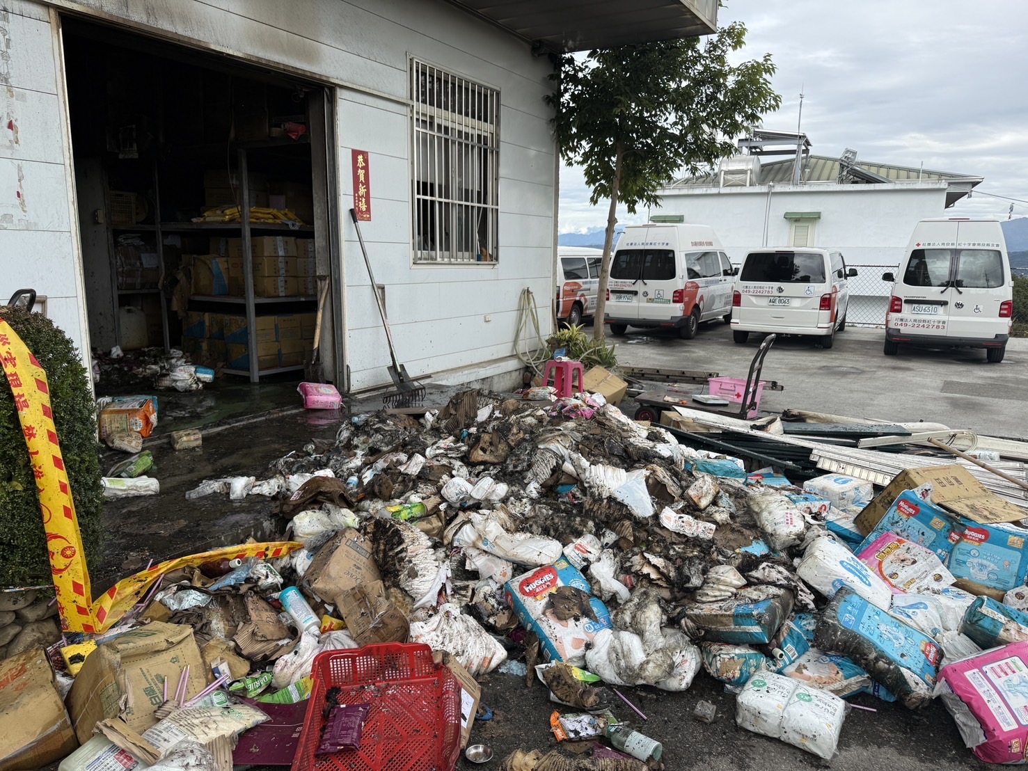 火災後受損物資堆置於建物外,部分民眾捐贈物資遭焚毀,後續將進行拆除清運與空間復原工程。