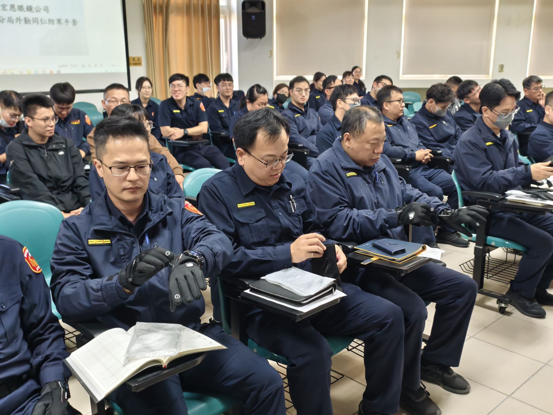 彰化分局員警於室內勤前會議中實際試戴宏恩眼鏡捐贈的「特殊戰略手套」，手套具備保暖、防風與防滑功能，適合寒流期間戶外與機車巡邏勤務使用，有助提升執勤舒適度與安全性。