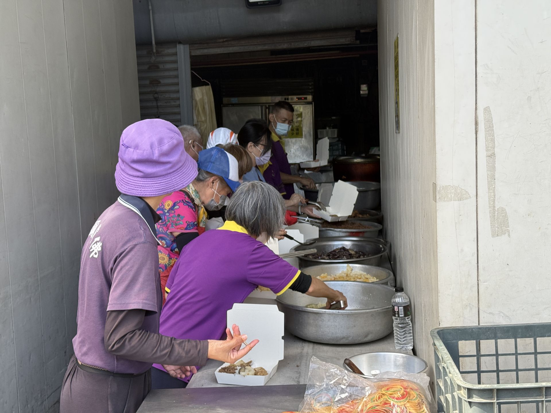 志工們從早上開始分工合作，洗菜、切菜、整理食材，為每日三百至五百份的便當做準備。