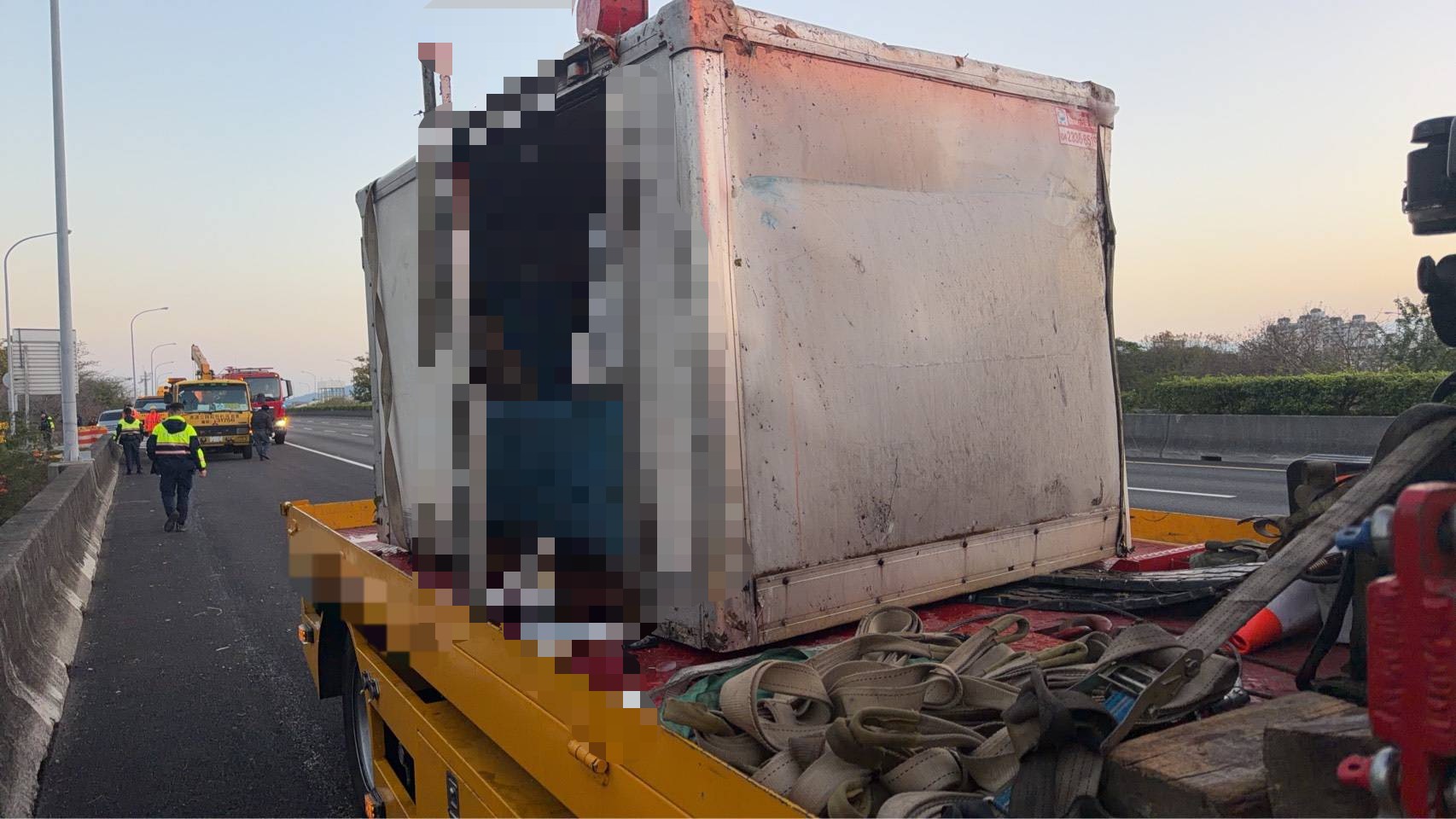 肇事小貨車經拖吊後移置路肩，車體嚴重變形，事故現場仍可見救援器材與拖吊設備。