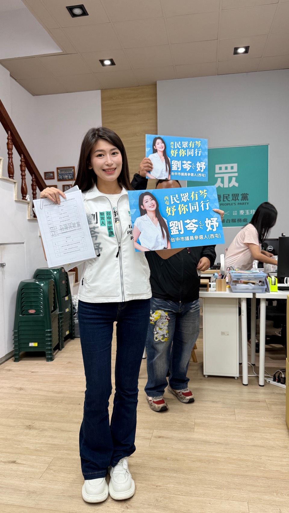 劉芩妤於民眾黨台中市黨部完成參選登記,手持文件與競選看板向支持者展示參選決心。