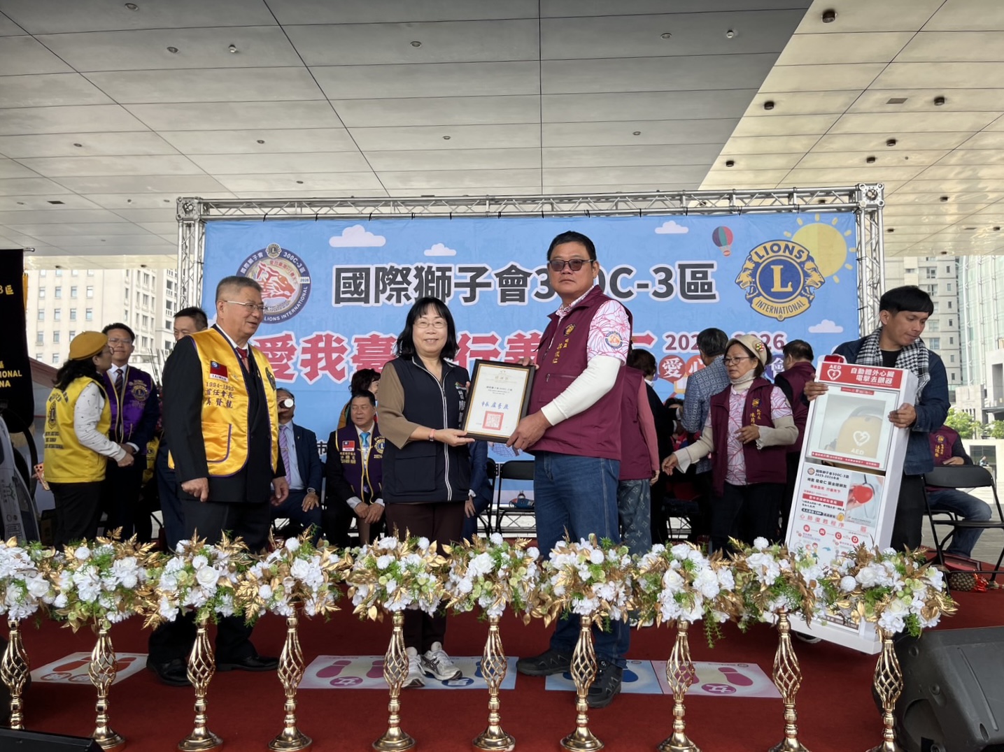 台中市政府社會局長 廖靜芝（左）代表受贈，國際獅子會300C-3區總監 梁俊仁（右）致贈AED，攜手強化社區照顧關懷據點急救量能，守護長輩生命安全。