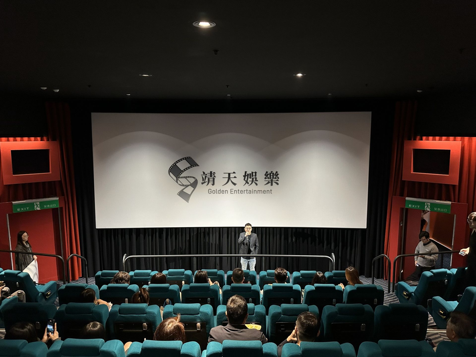 特映會現場，靖天電視台副總經理 陸靖天站在大銀幕前發表致詞，觀眾席坐滿期待觀影的影迷。靖天娛樂/提供